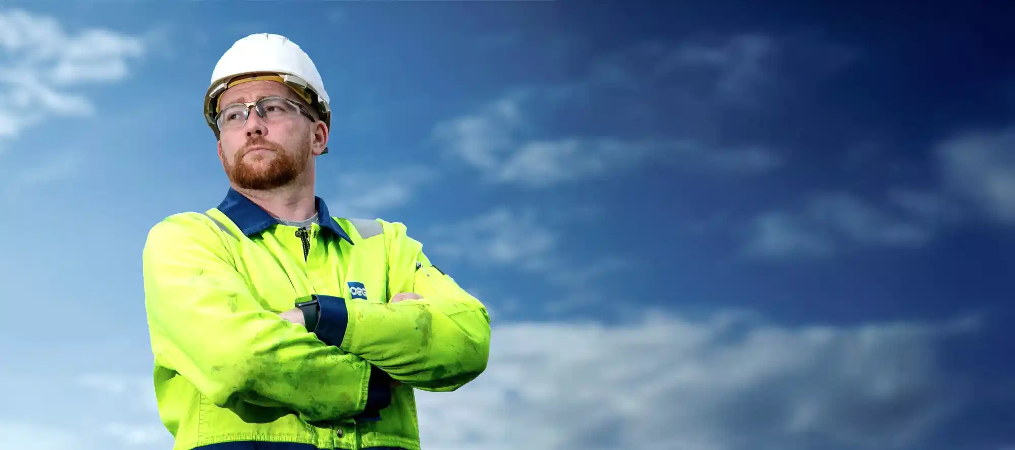 OEG worker with folded arms and blue sky in the background